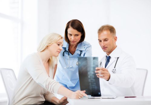 healthcare, medical and radiology concept - doctors with patient looking at x-ray