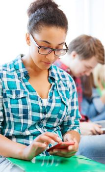 education concept - smiling international student girl with smartphone at school