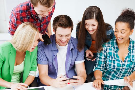 education concept - group of students looking into smartphone at school