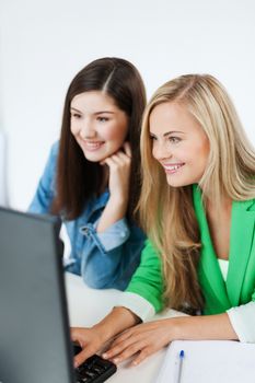 education concept - students looking at laptop at school