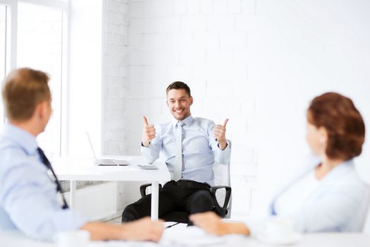 business concept - businessman showing thumbs up in office