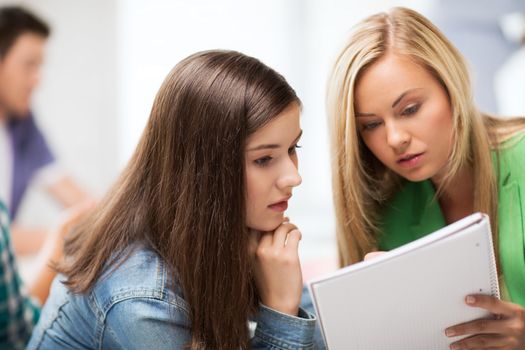 education concept - student girls looking at notebook at school