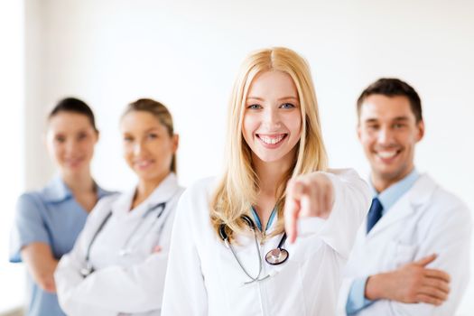 healthcare and medical concept - attractive female doctor in front of medical group