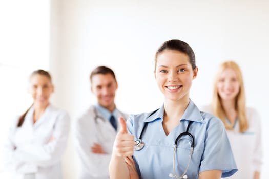 healthcare and medical concept - female doctor with group of medics showing thumbs up