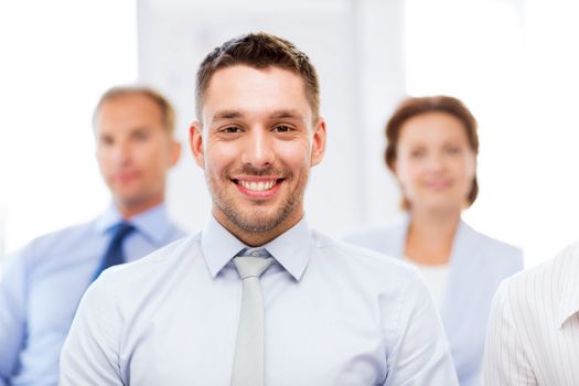 business concept - smiling handsome businessman with team in office