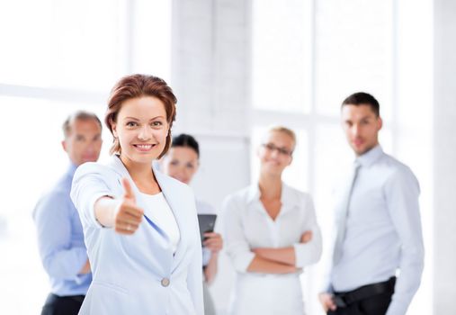 business concept - attractive businesswoman with team in office showing thumbs up