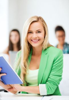 education concept - smiling young girl reading book at school