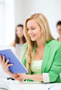 education concept - smiling young girl reading book at school