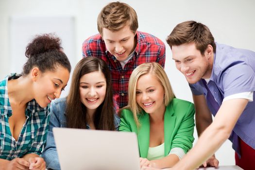 education and internet concept - group of international students looking at laptop at school