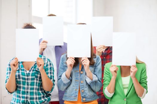 education concept - group of students covering faces with blank papers