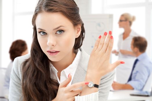 business and time management concept - businesswoman pointing at her watch