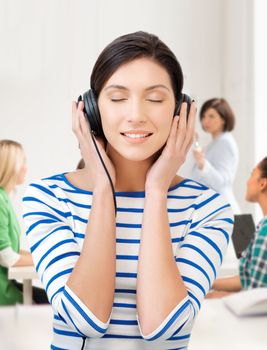 education and music concept - student girl in big headphones at school