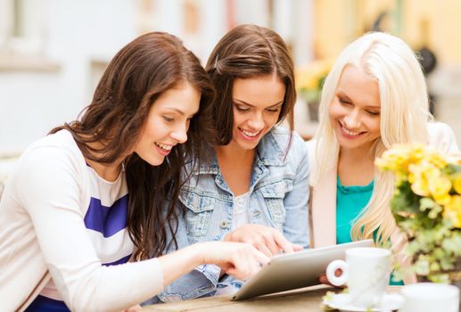 holidays, tourism and internet - beautiful girls looking at tablet pc in cafe outside