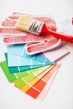 interior design and home renovation concept - paintbrush, gloves and pantone samplers