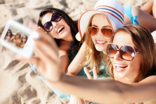 summer holidays, technology and beach concept - girls making self portrait on the beach