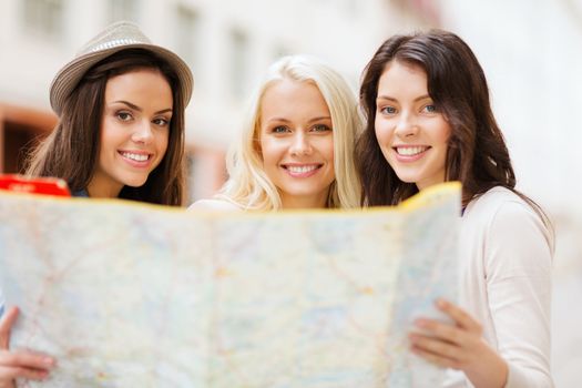 holidays and tourism concept - beautiful girls looking into tourist map in the city