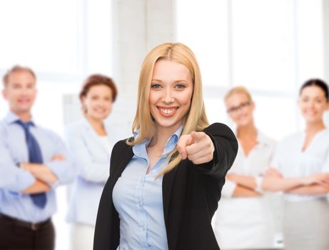 business concept - attractive young businesswoman pointing at you in office