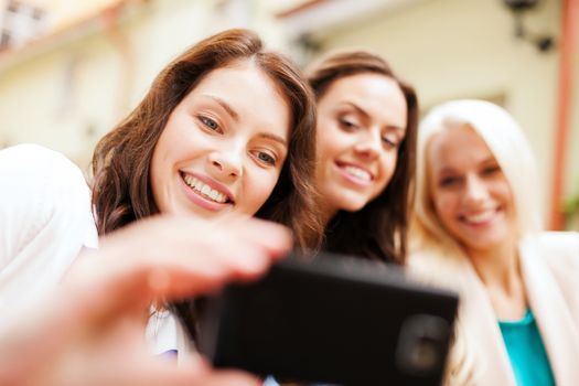 holidays and tourism concept - beautiful girls taking picture in cafe in city