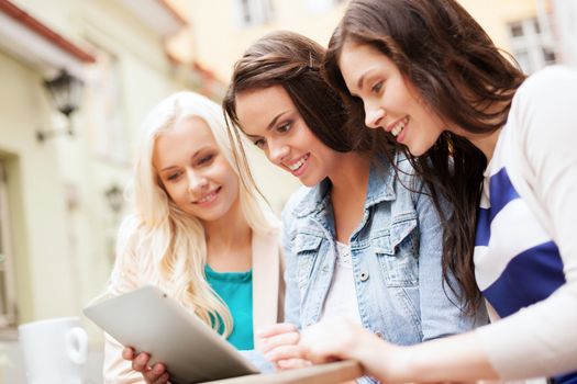 holidays, tourism and internet - beautiful girls looking at tablet pc in cafe outside