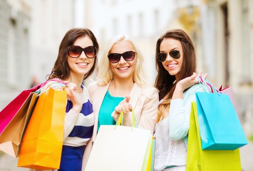 shopping and tourism concept - beautiful girls with shopping bags in ctiy