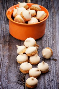 Arrangement of Swirled Meringue Topping in Orange Bowl isolated on Rustic Wooden background