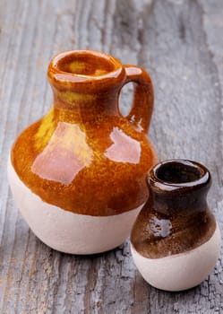 Two Little Handmade Earthenware Jugs isolated on Rustic Wooden background