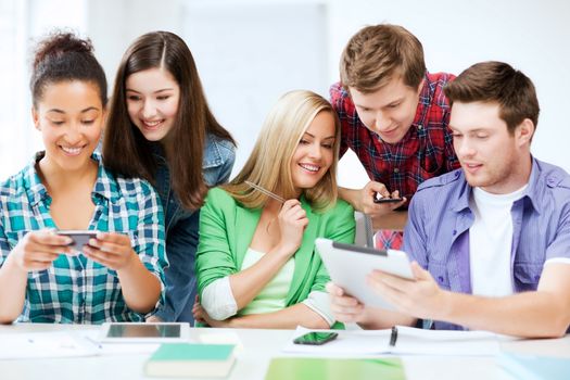 education, technology and internet - students looking at smartphones and tablet pc