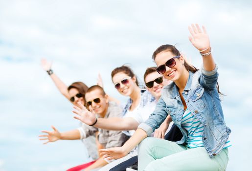 summer holidays and teenage concept - group of teenagers waving hands