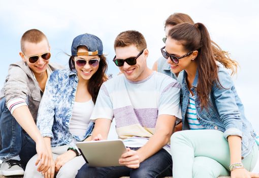 summer holidays, teenage and technology concept - group of teenagers looking at tablet pc