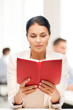 business and education concept - woman reading book in college or office