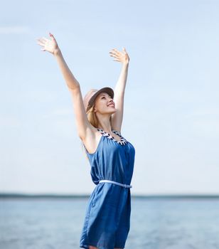 summer holidays and vacation - girl with hands up on the beach