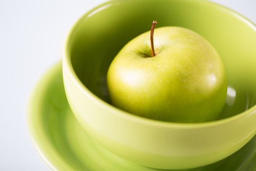 healthy food and cooking concept - green apple in green bowl