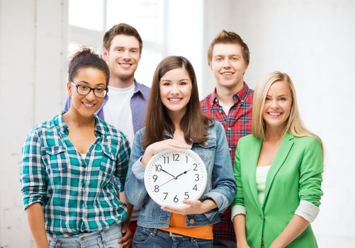 education and time concept - group of students at school with clock