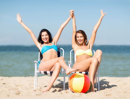 summer holidays and vacation - girls in bikinis sunbathing on the beach chairs