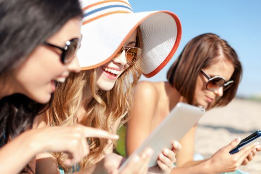 summer holidays, technology and internet concept - girls in bikinis with tablet pc sunbathing on the beach