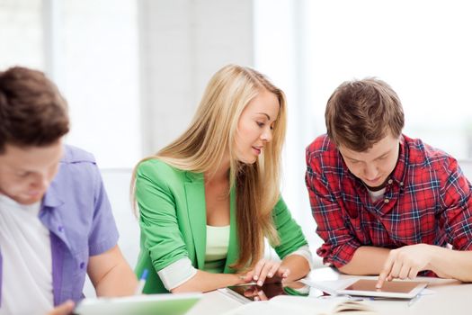 education and internet - smiling students browsing in tablet pc at school