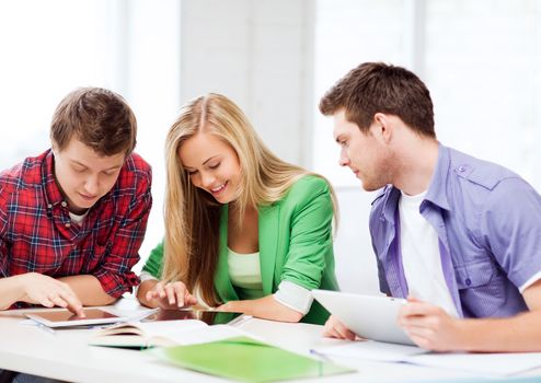 education and internet - smiling students browsing in tablet pc