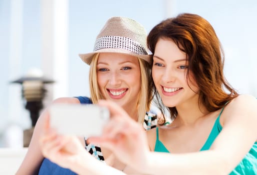 summer holidays and vacation - girls taking photo in cafe on the beach