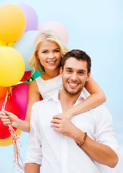 summer holidays, celebration and dating concept - couple with colorful balloons at seaside