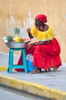 CARTAGENA, MAY 13: Palenquera woman with typical dress sells fruit on the Street on May 13, 2010 in Cartagena, Colombia. Palenqueras are a unique african ethnic group in the north of South America