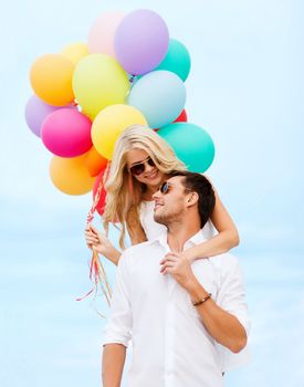 summer holidays, celebration and dating concept - couple with colorful balloons at seaside