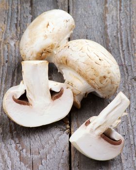 Raw Champignons Full Body and Halves isolated on Rustic Wooden background
