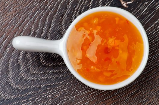 Thai Spicy Sauce in White Gravy Boat isolated on Wooden background. Top View