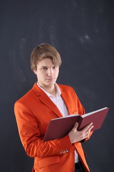 Portrait of a young, handsome man standing against the background of blackboard