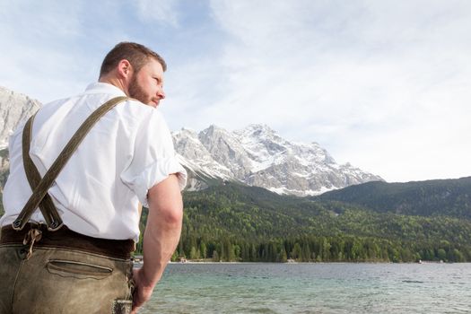 A traditional bavarian man at lake Eibsee with the Zugspitze mountain in the background