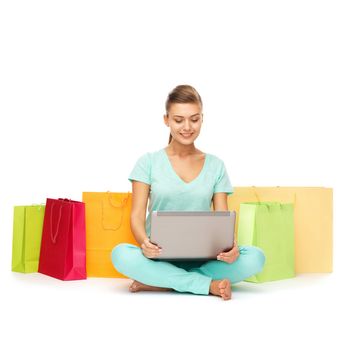 shopping, internet and home concept - woman with laptop and shopping bags