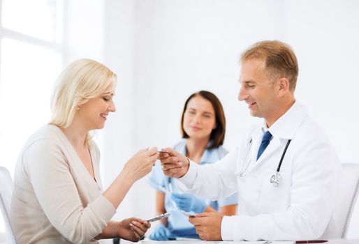 healthcare and medical concept - doctor giving tablets to patient in hospital