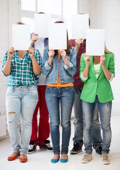 education concept - group of students covering faces with blank papers