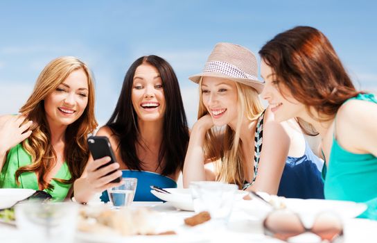 summer holidays, vacation and technology - girls looking at smartphone in cafe on the beach