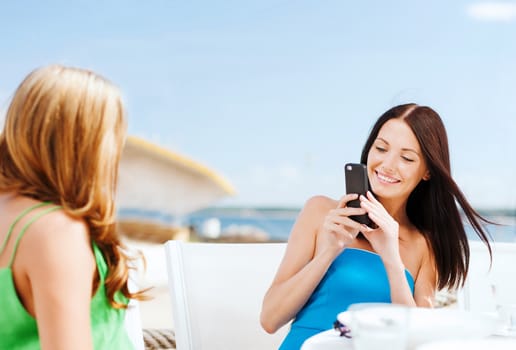 summer holidays, vacation and technology - girls taking photo with smartphone in cafe on the beach